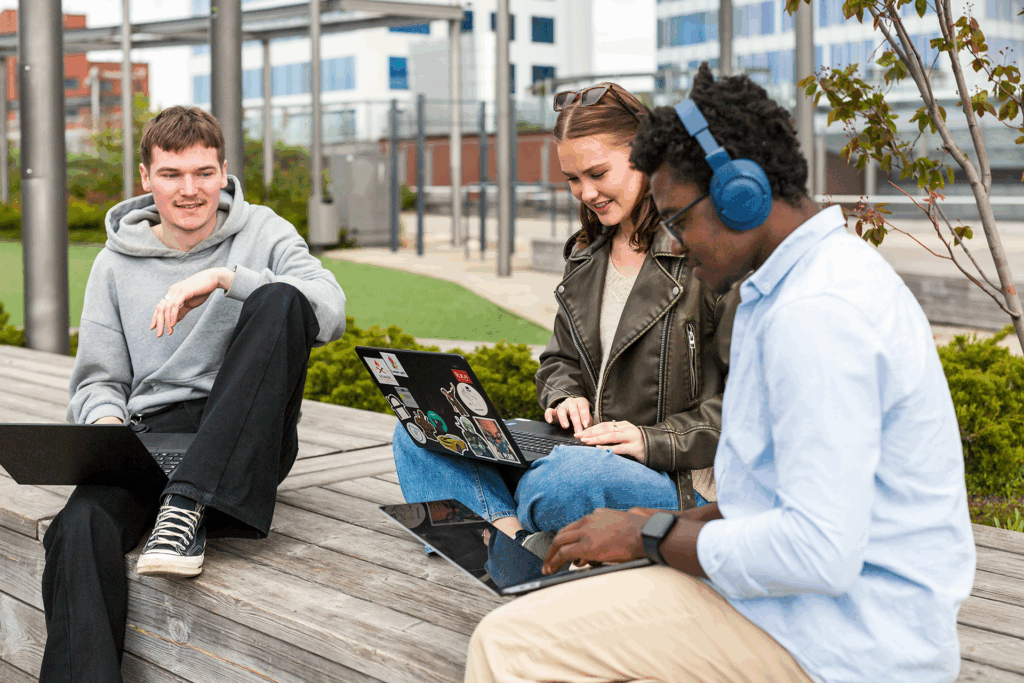 kolme opiskelijaa istuu ulkona